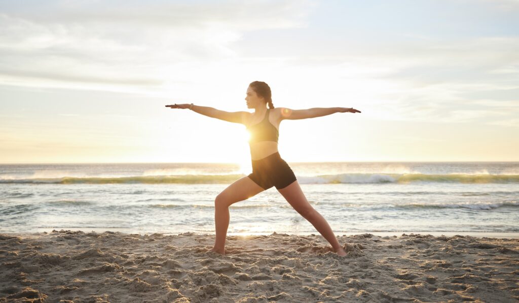 Woman, yoga and meditation on the beach for zen, spiritual wellness or workout in the sunset outdoo